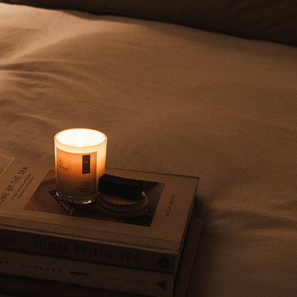 Weirli Raw Vanilla and Rice Milk Soy Candle lit on a bed