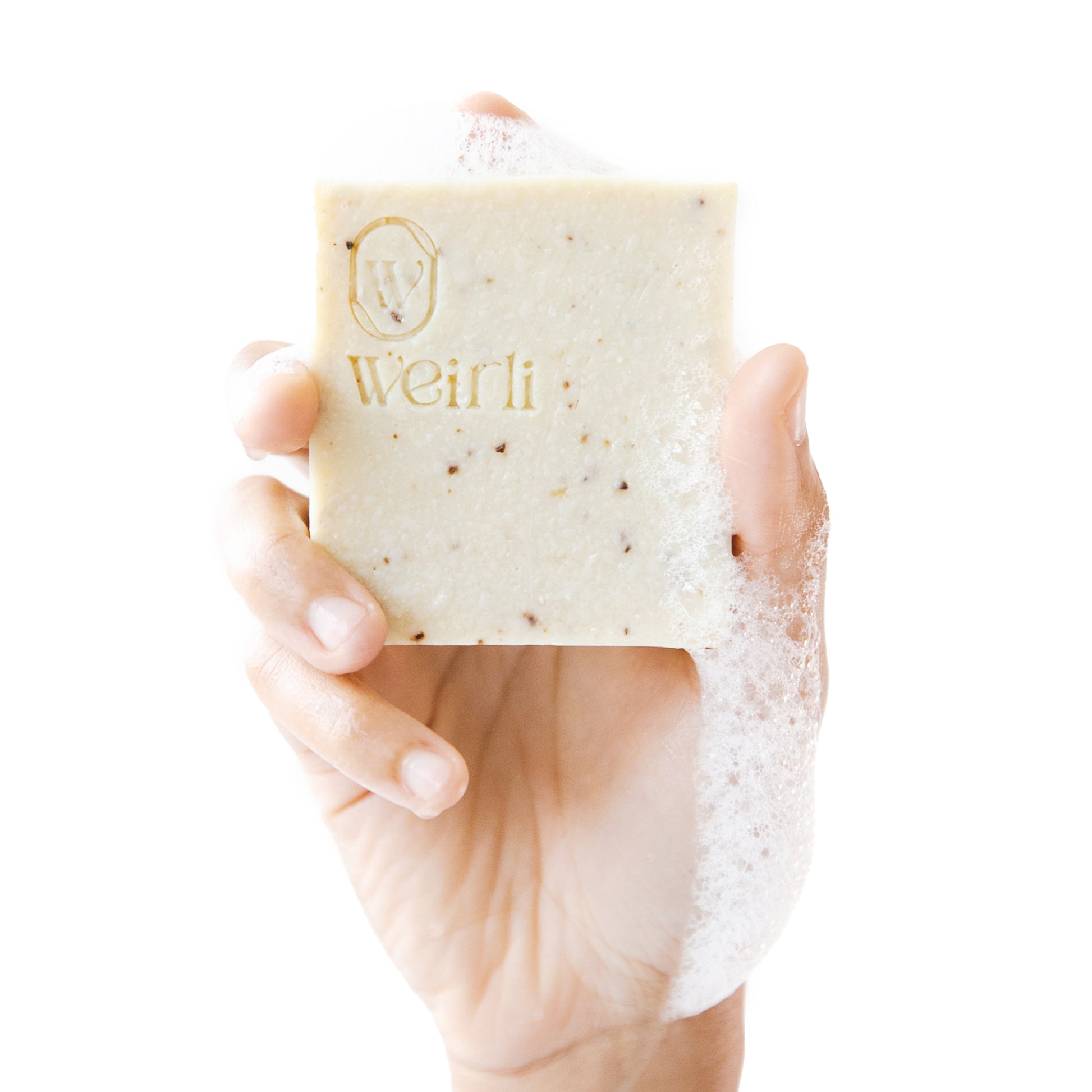 Soapy rice and black pepper soap square held up by a hand