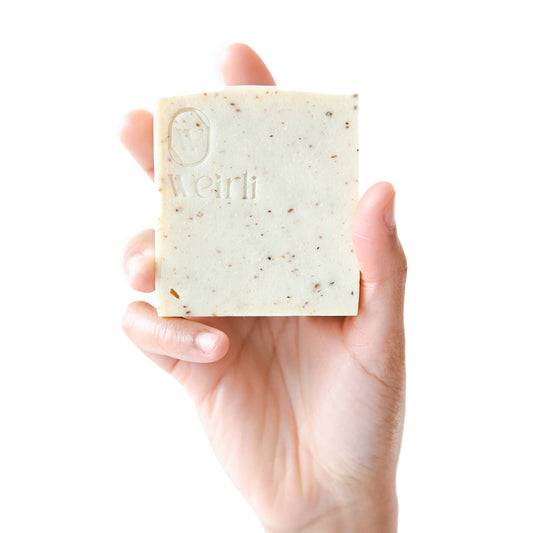 Rice and black pepper soap square held up by a hand