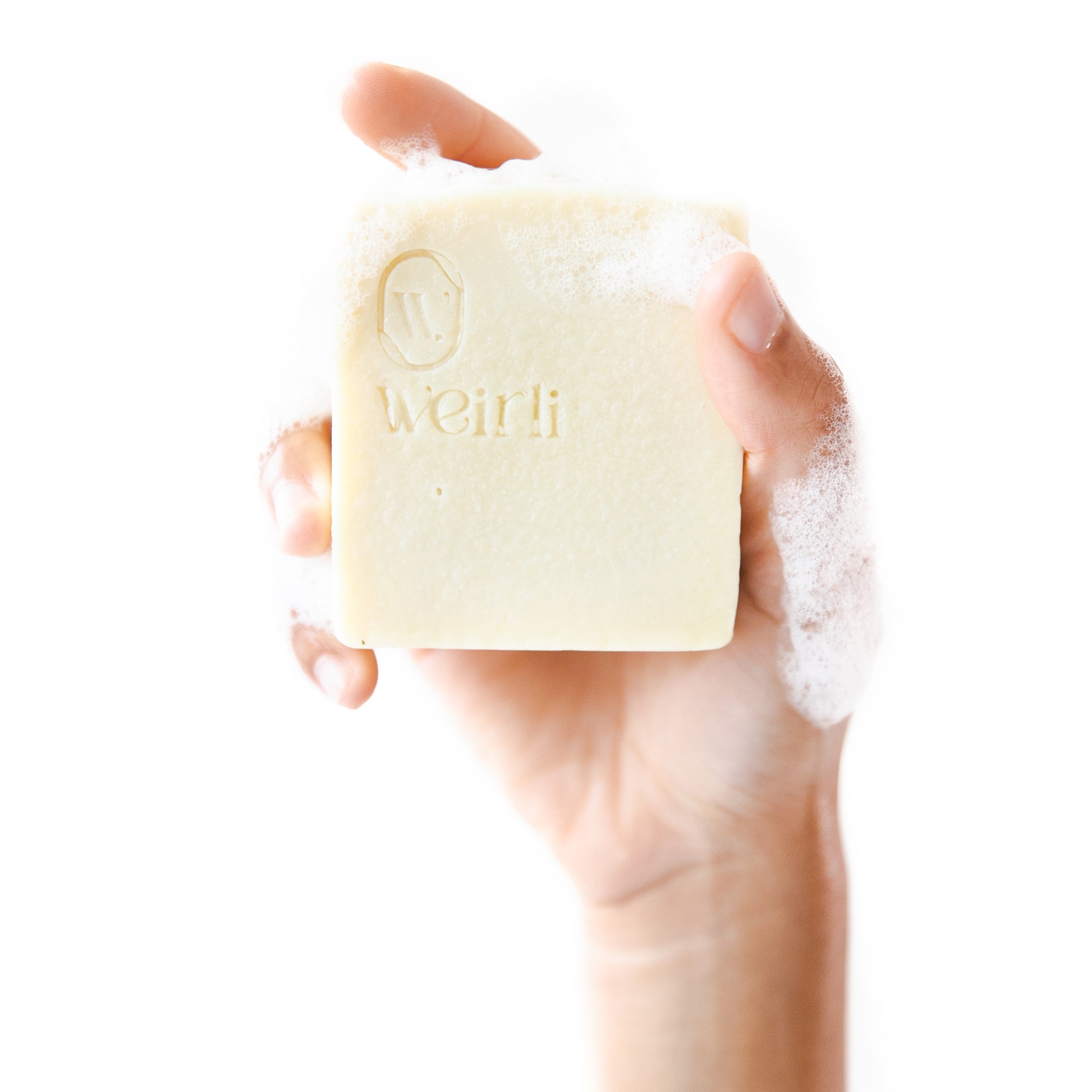 Soapy shea and oat soap square held up by a hand